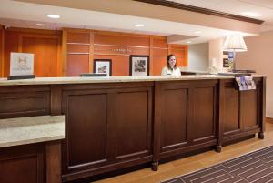 a woman standing at a counter in a waiting room at Hampton Inn Pittsburgh/Airport in Moon Township