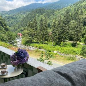 a vase of flowers on a balcony with a view of a mountain at Nanus Ayder Apart and Restoran in Rize