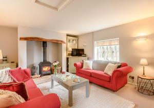 a living room with two red couches and a fireplace at Wisteria Cottage in Snape