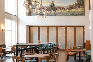 a dining room with tables and chairs and a painting on the wall at Hampton Inn & Suites Boerne in Boerne