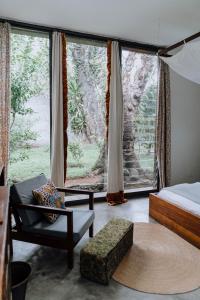 a room with a bed and a chair and a window at Kaliwa Lodge in Moshi