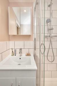 a white bathroom with a sink and a shower at Be London - The St John's Wood Residences in London