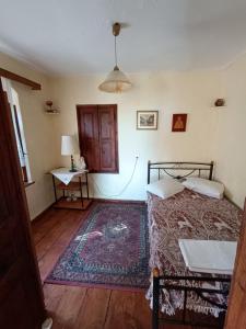 1 dormitorio con cama, mesa y alfombra en Archontiko Maros, en Mouresi