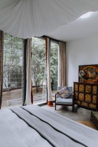 a bedroom with a bed and a chair and windows at Kaliwa Lodge in Moshi