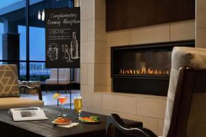 Embassy Suites By Hilton Syracuse Destiny USA في سيراكيوز: مطعم فيه موقد وطاولة فيها طعام ومشروبات