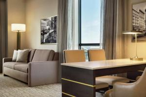 a living room with a couch and a desk in a room at Embassy Suites By Hilton Syracuse Destiny USA in Syracuse