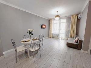 uma sala de estar com uma mesa e cadeiras e um sofá em Апартаменты в ЖК Only Sun em Prigorodnyy