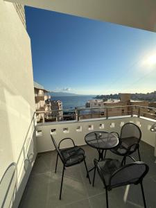 balcón con sillas, mesa y vistas al océano en Villa Idrizi en Sarandë
