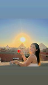 una mujer tomando una foto de la puesta de sol en mesho falcon Pyramids view inn, en El Cairo