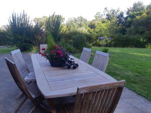 a wooden table with chairs and flowers on it at Chambre d'hôte cosy & zen in Saint-Jean-la-Poterie