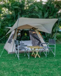 ein Zelt mit Stühlen und einem Tisch im Gras in der Unterkunft Shose Campsite in Shiri