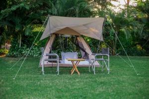 une tente avec 2 chaises et une table dans l'herbe dans l'établissement Shose Campsite, à Shiri