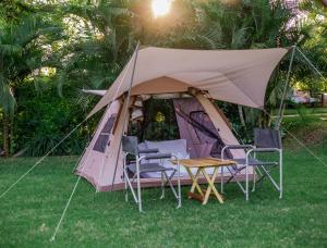 une tente avec des chaises et une table dans l'herbe dans l'établissement Shose Campsite, à Shiri