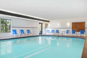 una piscina en una habitación de hotel con sillas y mesas azules en Hampton Inn Merrillville, en Merrillville