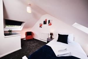 a bedroom with a white bed and a red chair at Cassia, 3 Bedrooms, Sleeps 5 