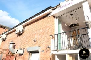 a brick building with a balcony on the side of it at Bee Stays - Crossbar Hotel One-Bedroom Flats in Warrington