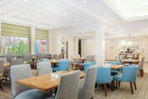 un restaurante con mesas de madera y sillas azules en Hilton Garden Inn Roanoke Rapids, en Roanoke Rapids