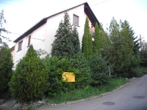 a house with a sign in front of some bushes at Mandula Vendégház in Eger