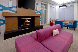 a living room with a pink couch and a fireplace at Hilton Garden Inn Albuquerque Airport in Albuquerque