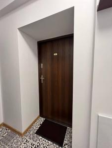 drewniane drzwi w pokoju z podłogą wyłożoną kafelkami w obiekcie Best for 2 w mieście Pabianice