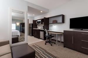 a hotel room with a desk with a television and a bed at Home2 Suites by Hilton Charlotte University Research Park in Charlotte