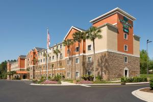a large building with palm trees in a parking lot at Homewood Suites Jacksonville Deerwood Park in Jacksonville