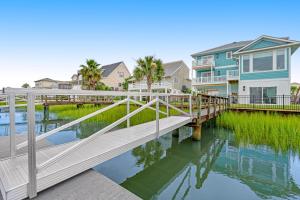 a wooden bridge over a body of water with houses at The Blue Whale Inn in Ocean Isle Beach