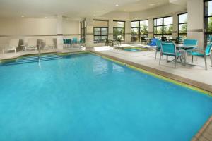 a large swimming pool with blue chairs and tables at Hilton Garden Inn College Station in College Station