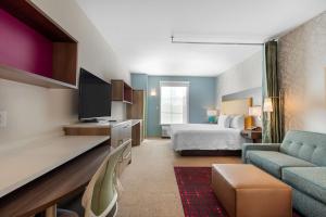 奥利夫布兰奇Home2 Suites By Hilton Olive Branch的一间带床和客厅的酒店房间