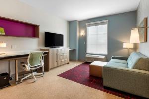 奥利夫布兰奇Home2 Suites By Hilton Olive Branch的客厅配有沙发和书桌及电视