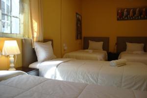 una habitación de hotel con 3 camas y una lámpara en Lion Backpackers, en Lima