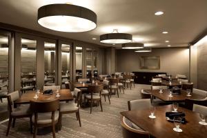 een restaurant met houten tafels en stoelen in een kamer bij DoubleTree by Hilton Hotel Dallas Campbell Centre in Dallas