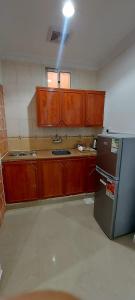 a kitchen with wooden cabinets and a refrigerator at سما رفحاء للشقق المخدومة in Rafha