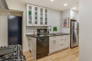 a kitchen with white cabinets and a black refrigerator at Beautiful & Stylish 2 BDR Hosted By StayRafa (1F) in Philadelphia