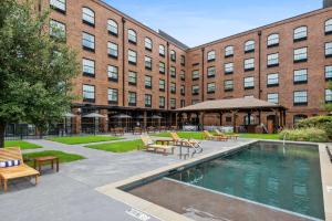 a building with a swimming pool in front of a building at NYLO Dallas Plano Hotel, Tapestry Collection by Hilton in Plano