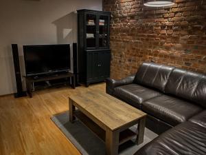 uma sala de estar com um sofá de couro e uma televisão em Apartament za ratuszem em Tarnowskie Góry