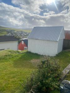 Miðvágur的住宿－Cosy house in the old village，一座大白色的建筑,位于草地山丘上