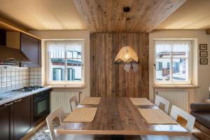 cocina con mesa de madera, sillas y ventanas en Ciasa Buro - Zen, en Moena