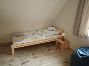 a small bed in a room with a wooden floor at 4domki in Krośnice