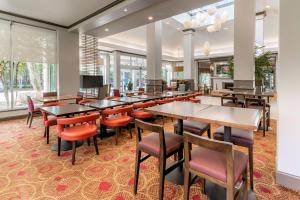 un restaurante con mesas, sillas y ventanas en Hilton Garden Inn Houston/The Woodlands, en The Woodlands