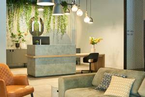 a lobby with a couch and a desk with plants at Nena Apartments Bochum City in Bochum