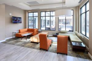 a living room with orange furniture and windows at Hilton Garden Inn Reagan National Airport in Arlington
