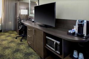 a hotel room with a desk with a flat screen tv at Hilton Garden Inn Reagan National Airport in Arlington
