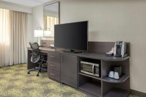 a hotel room with a desk with a television and a chair at Hilton Garden Inn Reagan National Airport in Arlington
