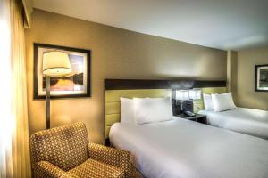a hotel room with two beds and a chair at Hilton Garden Inn Reagan National Airport in Arlington