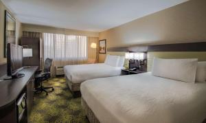a hotel room with two beds and a flat screen tv at Hilton Garden Inn Reagan National Airport in Arlington +37 photos