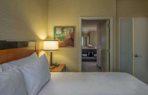a bedroom with a white bed with a lamp and a doorway at Hilton Garden Inn Reagan National Airport in Arlington