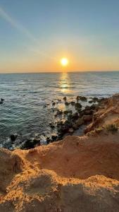 a sunset over the ocean with rocks in the water at Pearl of the sea in H̱adera