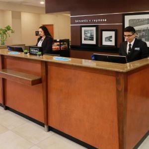 two people sitting at a reception counter in a lobby at Hampton by Hilton Reynosa Zona Industrial in Reynosa