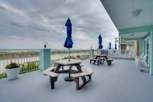 a patio with two picnic tables and a blue umbrella at Cozy Oceanfront Condo with Pool and Beach Access! in Wildwood Crest